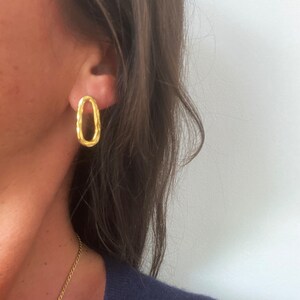 May include: Gold oval-shaped earrings with a textured design.