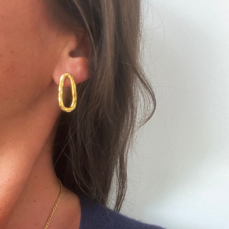 May include: Gold oval-shaped earrings with a textured design.