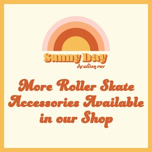 Op de afbeelding: Een afbeelding met een regenboogvormige boog en de tekst "Sunny Day by alison rae". Onder de tekst staat de zin "More Roller Skate Accessories Available in our Shop" in een retro-lettertype.
