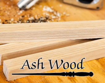 以下が含まれることがあります： 「Ash Wood」の文字がスタイリッシュなフォントで書かれた、トネリコの木の板のクローズアップ。下部には黒い杖があります。木材は明るい茶色で、木目が見えます。