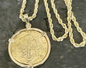 May include: A gold coin pendant with a cross design, set in a gold bezel, on a gold rope chain.