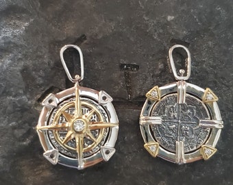 Op de afbeelding: Twee zilveren en gouden hangers met een kompas- en een muntontwerp. Beide hangers hebben een kleine diamant in het midden.