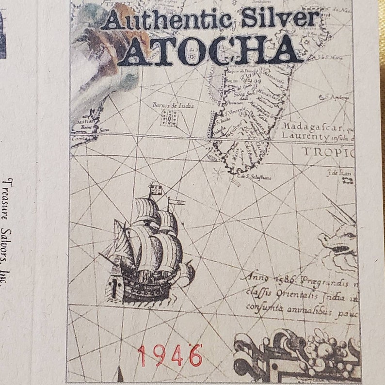 May include: A vintage map with a ship illustration and the text "Authentic Silver ATOCHA 1946" printed on it. The map shows the location of Madagascar and the Tropic of Capricorn.