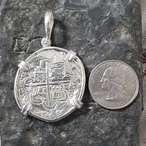 K&ouml;nnte beinhalten: Silberm&uuml;nzenanh&auml;nger mit Kreuzdesign und &Ouml;se. Die M&uuml;nze ist etwa so gro&szlig; wie eine US-amerikanische 25-Cent-M&uuml;nze.