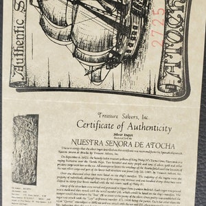 K&ouml;nnte beinhalten: Ein Echtheitszertifikat f&uuml;r einen Silberbarren, der aus dem Wrack der Nuestra Se&ntilde;ora de Atocha geborgen wurde. Das Zertifikat zeigt eine Schwarzwei&szlig;illustration des Schiffes und enth&auml;lt den Text "Nuestra Se&ntilde;ora de Atocha" und "Treasure Salvors, Inc."
