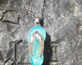 May include: A silver chain necklace with a blue glass pendant shaped like a flip-flop.