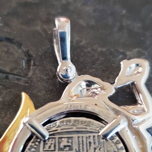 May include: Silver pendant featuring a detailed design of a mermaid riding a dolphin, with a silver coin embedded in the centre. The coin has a detailed design and the inscription "J Spirit &copy;" is visible on the pendant.