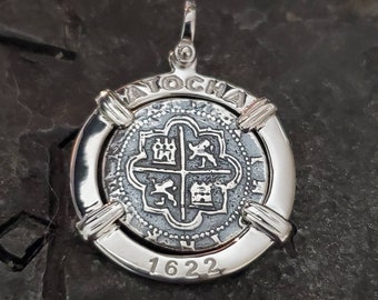 Op de afbeelding: Zilveren hanger met een replica van een Spaanse munt uit 1622 met de inscriptie "ATOCHA" en "1622".