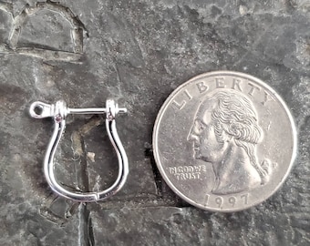 May include: Silver earring finding with a U-shaped hook and a small pin. The finding is shown next to a US quarter for size comparison.