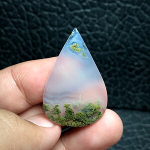 May include: A teardrop-shaped agate cabochon with a pink and white base and green moss inclusions.