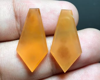 May include: Two orange gemstone pendants in a diamond shape. The pendants are translucent and have a slight orange hue.