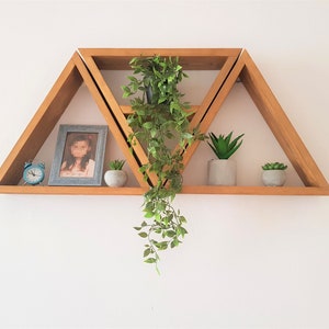Peut inclure: Un ensemble de trois &eacute;tag&egrave;res triangulaires en bois avec un design g&eacute;om&eacute;trique. Les &eacute;tag&egrave;res sont empil&eacute;es les unes sur les autres et sont d&eacute;cor&eacute;es de plantes et d'une photo encadr&eacute;e.