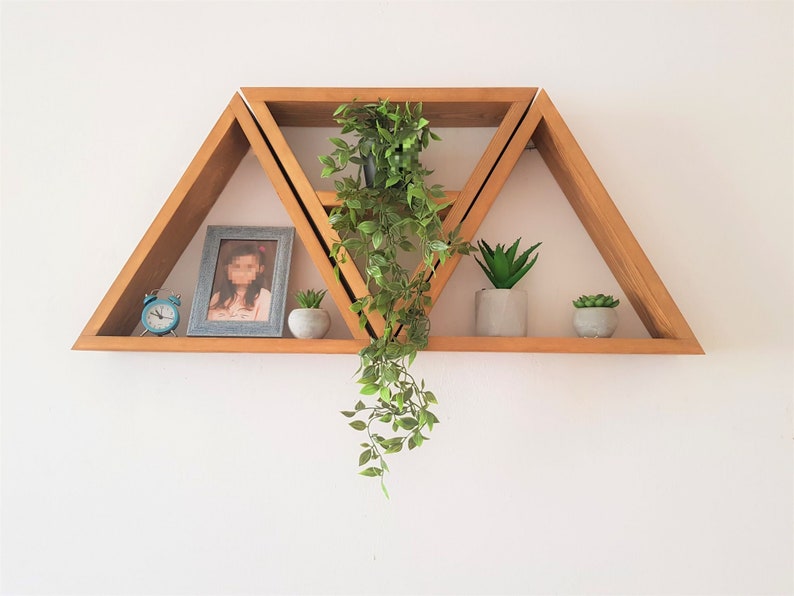 Peut inclure: Un ensemble de trois &eacute;tag&egrave;res triangulaires en bois avec un design g&eacute;om&eacute;trique. Les &eacute;tag&egrave;res sont empil&eacute;es les unes sur les autres et sont d&eacute;cor&eacute;es de plantes et d'une photo encadr&eacute;e.