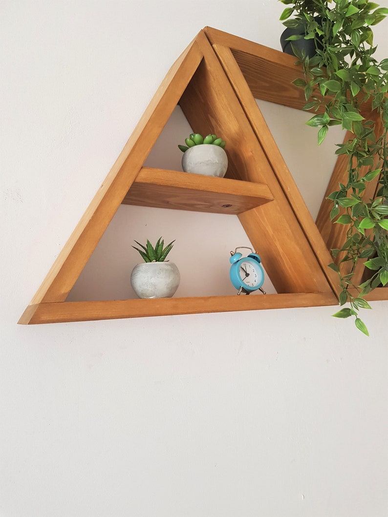 Peut inclure: Une &eacute;tag&egrave;re triangulaire en bois avec trois tablettes. Les tablettes sont d&eacute;cor&eacute;es de petites plantes en pot et d'un r&eacute;veil bleu.