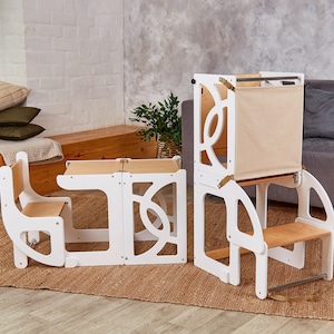 May include: White wooden children's play set with a table and chair, a step stool, and a learning tower with a canvas panel. The set is on a light brown rug.