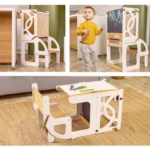 May include: A white wooden learning tower with a chalkboard and a small table and chair. The tower has a step stool and a safety rail. The table and chair are also white wood. The tower is designed to help children reach higher surfaces safely.