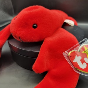 May include: Red plush lobster beanie baby toy with a white tag that says "Ty" and "Beanie Original".