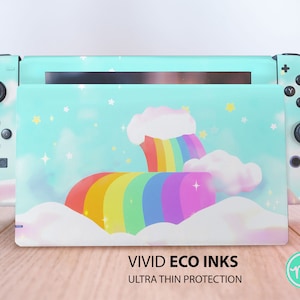 Op de afbeelding: Een turquoise Nintendo Switch console skin met een regenboog- en wolkenontwerp. De skin heeft een regenboog die over pluche witte wolken boogt met een lichtblauwe achtergrond en glinsterende sterren. De tekst "VIVID ECO INKS ULTRA THIN PROTECTION" is onder de afbeelding gedrukt.