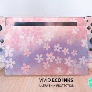 Może przedstawiać: Skórka na konsolę Nintendo Switch w kolorze różowym i fioletowym z wzorem wiśni. Skórka jest zaprojektowana tak, aby pasowała do konsoli Nintendo Switch i kontrolerów. Skórka wykonana jest z cienkiego, trwałego materiału, który chroni konsolę przed zarysowaniami i brudem. Skórka jest łatwa w aplikacji i usuwaniu. Skórka jest również dostępna w innych kolorach i wzorach.  VIVID ECO INKS ULTRA THIN PROTECTION