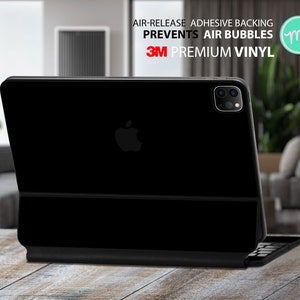 Può includere: iPad Pro nero con una custodia per tastiera nera. La custodia ha il logo 3M e il testo "AIR-RELEASE ADHESIVE BACKING PREVENTS AIR BUBBLES 3M PREMIUM VINYL".