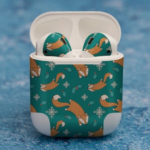 May include: White wireless charging case with a teal and green pattern featuring a repeating design of foxes with holly leaves and snowflakes.