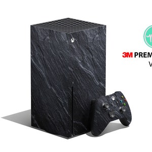 Könnte beinhalten: Schwarze und graue Xbox Series X Konsole mit einer Steinschiefer-Design-Haut. Die Konsole steht neben einem passenden schwarzen und grauen Xbox-Controller.