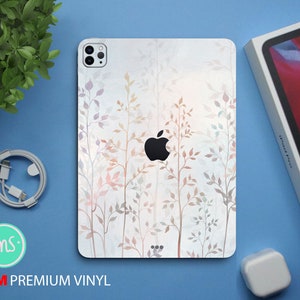 May include: A white iPhone case with a floral design. The design features delicate branches with small leaves in shades of pink, peach, and gray. The case has a clear apple logo in the center.