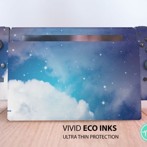 Op de afbeelding: Een Nintendo Switch-console met een aangepaste skin met een hemels ontwerp. De skin toont een blauwe lucht met witte wolken en sterren. De tekst "VIVID ECO INKS ULTRA THIN PROTECTION" is zichtbaar.