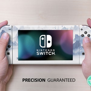 May include: A white Nintendo Switch console with a blue and white mountain landscape design. The console has the Nintendo Switch logo and the text "NINTENDO SWITCH." The text "PRECISION GUARANTEED" is printed below the console.