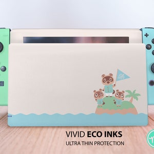Può includere: Una skin per Nintendo Switch di colore blu chiaro e beige con una grafica di Tom Nook e altri personaggi di Animal Crossing su un'isola. Il testo "VIVID ECO INKS ULTRA THIN PROTECTION" è stampato sotto l'immagine.