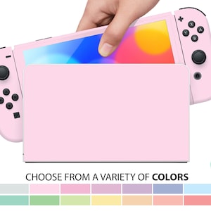 Può includere: Una console Nintendo Switch rosa con una custodia protettiva rosa. La console è aperta e lo schermo mostra un gradiente di colori. L'immagine mostra anche una varietà di opzioni di colore per la custodia.