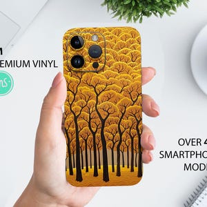 Puede incluir: Una funda para teléfono con una pegatina de vinilo 3M premium que presenta un patrón de árboles amarillos y marrones. El texto "3M PREMIUM VINYL" es visible en el lado izquierdo de la imagen. El texto "OVER 400 SMARTPHONE MODELS" es visible en el lado derecho de la imagen.