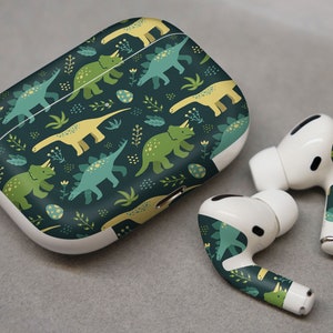 May include: A white Airpods case with a green, yellow and white dinosaur pattern. The case is closed and the Airpods are not visible. The Airpods are also shown separately with the same dinosaur pattern.