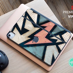 May include: A geometric patterned vinyl skin for a tablet or laptop. The design features a mix of blue, red, white, and black geometric shapes on a beige background. The skin is labeled "3M Premium Vinyl".
