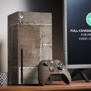 Puede incluir: Un kit de cobertura completa para una consola de juegos, con un diseño texturizado de aspecto metálico. El kit incluye una piel para la consola y una piel para el mando. El texto en la pantalla del televisor dice "FULL-COVERAGE KIT FOR PROTECT EVERY CORNER".