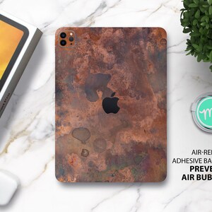 May include: A copper-toned phone case with a distressed, textured finish. The case has a cutout for the Apple logo and a camera lens. The text "AIR-RELEASE ADHESIVE BACKING PREVENTS AIR BUBBLES" is printed on a white background.