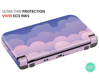 以下が含まれることがあります： 雲のパターンが施された、紫とピンクのニンテンドー3DS XLコンソールスキン。スキンには「ウルトラシン保護ビビッドエコインク」とラベルが貼られています。
