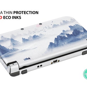 May include: A white Nintendo 3DS XL console with a blue and white mountain landscape design. The text "ULTRA THIN PROTECTION" and "VIVID ECO INKS" is printed on the top of the console.