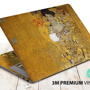 Puede incluir: Una piel de portátil dorada con una pintura de una mujer con un vestido dorado. La pintura es una reproducción de "El Beso" de Gustav Klimt.