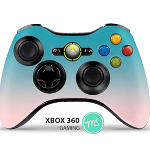 Puede incluir: Un mando Xbox 360 con un degradado de azul y rosa, botones negros y un logotipo de Xbox verde. El texto "XBOX 360 GAMING" est&aacute; impreso en el mando, junto con un peque&ntilde;o c&iacute;rculo verde con las letras "ms" en su interior.