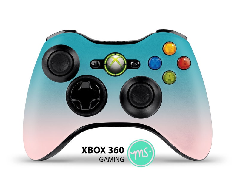 Puede incluir: Un mando Xbox 360 con un degradado de azul y rosa, botones negros y un logotipo de Xbox verde. El texto "XBOX 360 GAMING" est&aacute; impreso en el mando, junto con un peque&ntilde;o c&iacute;rculo verde con las letras "ms" en su interior.