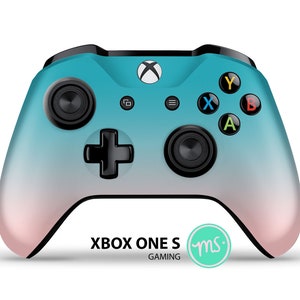 Puede incluir: Un mando Xbox One S de color azul turquesa y rosa con botones negros y un logotipo de Xbox blanco. El mando tiene un dise&ntilde;o degradado que pasa de azul turquesa a rosa. El texto "XBOX ONE S GAMING" est&aacute; impreso en la parte inferior del mando, y un peque&ntilde;o c&iacute;rculo verde con las letras "ms" est&aacute; impreso a la derecha del texto.