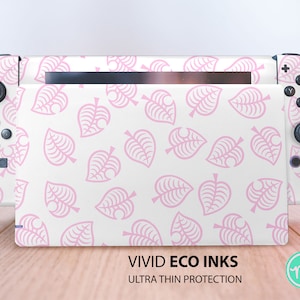 May include: A white Nintendo Switch console with a pink leaf pattern. The design covers the console and controllers. The text "VIVID ECO INKS" and "ULTRA THIN PROTECTION" is visible at the bottom.