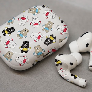 May include: White wireless earbuds with a case featuring a repeating pattern of black and white bears wearing colorful life preservers.