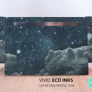 Puede incluir: Una piel para consola Nintendo Switch de color azul oscuro con un diseño de cielo nocturno estrellado y nubes blancas. La piel incluye el texto "VIVID ECO INKS ULTRA THIN PROTECTION".