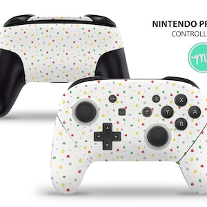 May include: White Nintendo Pro Controller with a colorful pattern of red, yellow, and green dots and leaves. The controller has a black faceplate and black buttons.