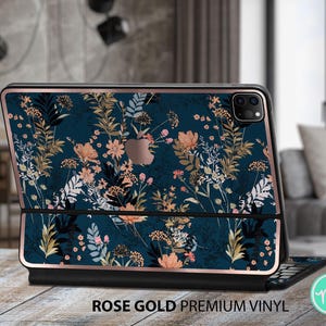 Op de afbeelding: Een roze gouden laptop skin met een bloemenpatroon in tinten blauw, roze en bruin. Het ontwerp bevat een verscheidenheid aan bloemen en bladeren, wat een delicate en vrouwelijke esthetiek creëert.