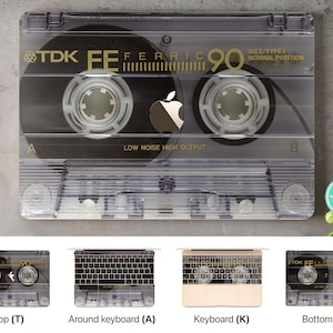 May include: A clear plastic cassette tape with a black label. The label has the text "TDK FE FERRIC 90 IECI TYPE! NORMAL POSITION" and a black Apple logo. The cassette tape is on a gray background.