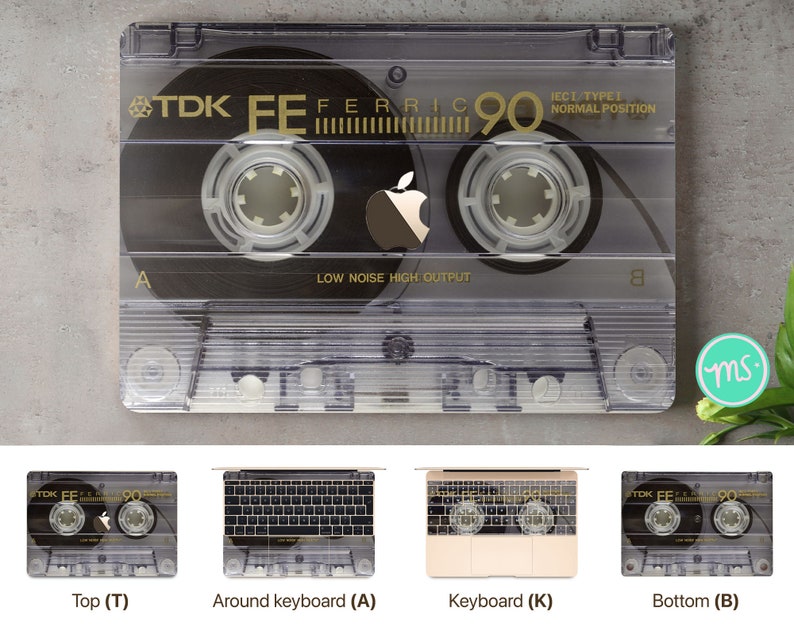 May include: A clear plastic cassette tape with a black label. The label has the text "TDK FE FERRIC 90 IECI TYPE! NORMAL POSITION" and a black Apple logo. The cassette tape is on a gray background.