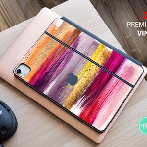 May include: A colorful abstract design iPad skin with pink, red, yellow, and gold brushstrokes. The skin is made with 3M premium vinyl.